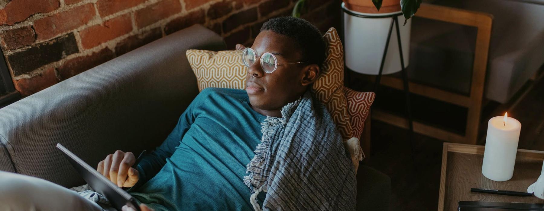 a man looks at his tablet while lying on his living room couch